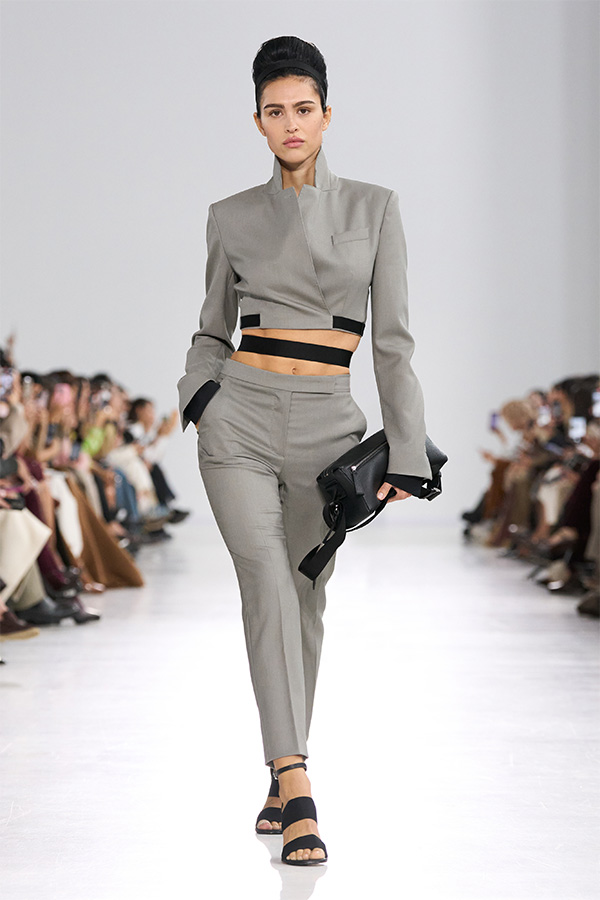 Max-Mara-Show Frühjahr/Sommer 2026 – Anzugslook in Grau mit Jacke und Hose mit schwarzer Tasche in der Hand.