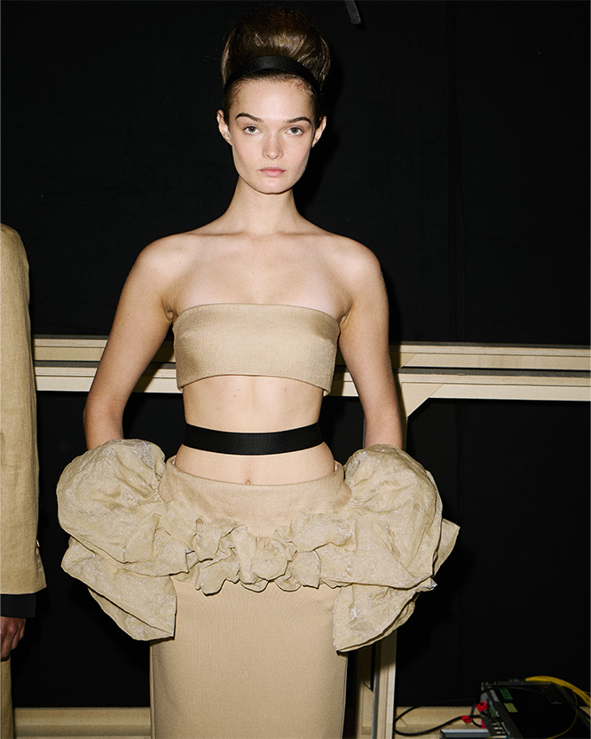 Max-Mara-Show Frühjahr/Sommer 2026 – Backstage-Aufnahme von Model mit Bandeau-Top und Rock in Beige mit Volants.