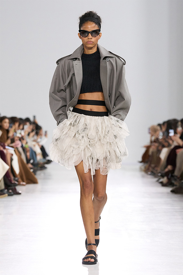 Max-Mara-Show Frühjahr/Sommer 2026 – Look mit Cropped-Trenchcoat in Grau und weißem Rock.